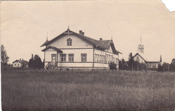 Kirkonkylän kansakoulu, takana näkyy kirkko. Kuva: Seuran arkisto (Siilin).